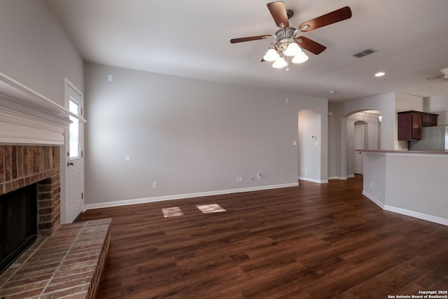 unfurnished living room with a brick fireplace, dark hardwood / wood-style floors, and ceiling fan