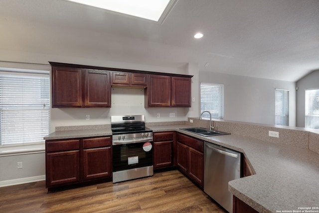 kitchen with lofted ceiling, sink, dark hardwood / wood-style flooring, kitchen peninsula, and stainless steel appliances