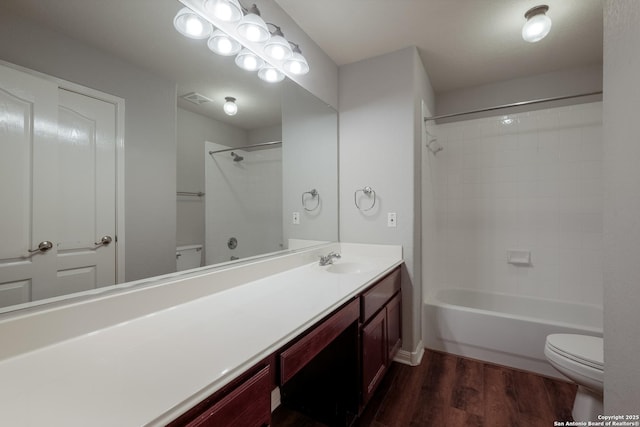 full bathroom with vanity, hardwood / wood-style floors, tiled shower / bath combo, and toilet