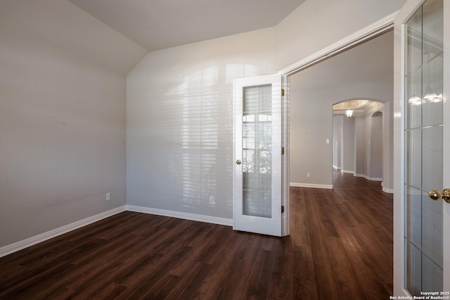 spare room with lofted ceiling and dark wood-type flooring