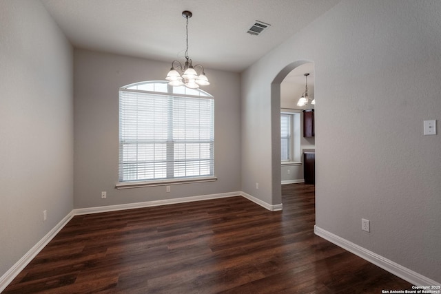 unfurnished room featuring an inviting chandelier and dark wood-type flooring