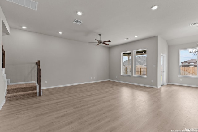 unfurnished living room featuring plenty of natural light, ceiling fan with notable chandelier, and light hardwood / wood-style floors