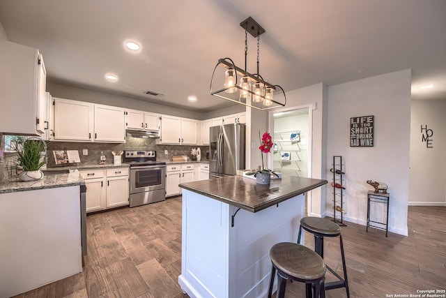 kitchen featuring decorative backsplash, appliances with stainless steel finishes, hanging light fixtures, and white cabinets