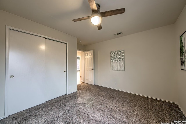 unfurnished bedroom with dark colored carpet, ceiling fan, and a closet