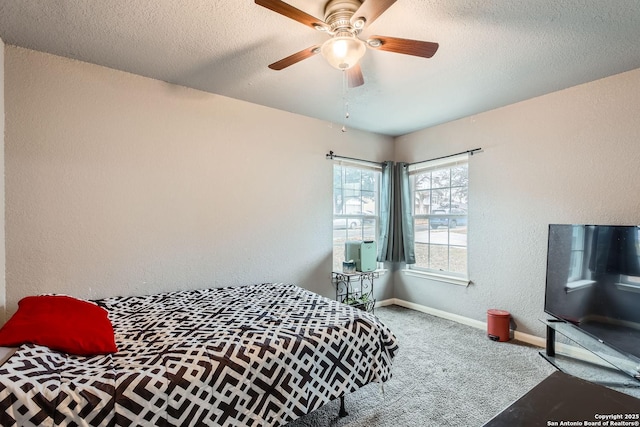 carpeted bedroom featuring ceiling fan and a textured ceiling