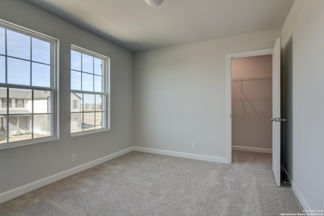 unfurnished bedroom featuring light carpet, a spacious closet, and a closet