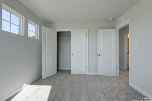 unfurnished bedroom with a closet and light carpet