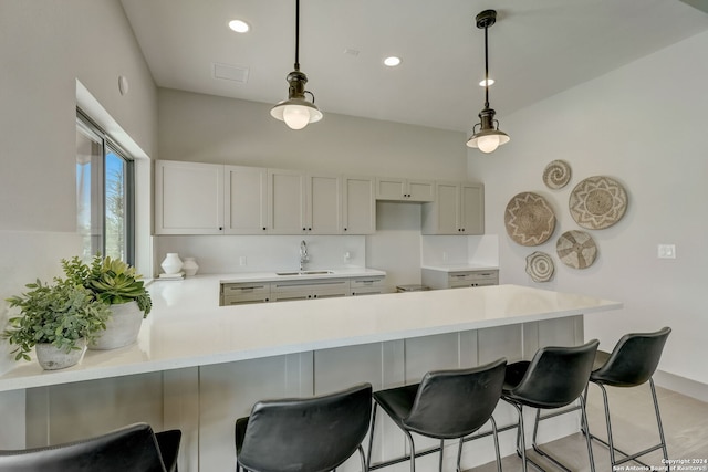 kitchen with sink, a breakfast bar, hanging light fixtures, backsplash, and kitchen peninsula