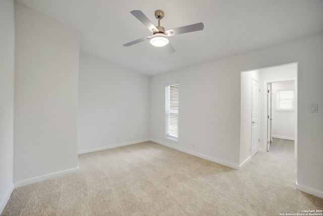 empty room with ceiling fan, a healthy amount of sunlight, and light carpet