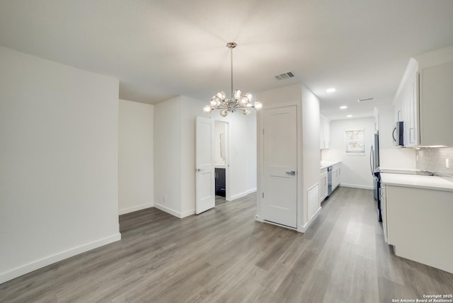 interior space with stainless steel appliances, pendant lighting, white cabinets, and light wood-type flooring