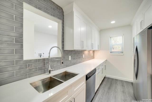 kitchen with sink, decorative backsplash, stainless steel appliances, and white cabinets