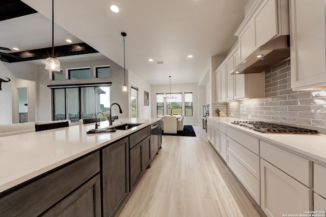 kitchen featuring tasteful backsplash, white cabinetry, hanging light fixtures, stainless steel gas cooktop, and dark brown cabinets