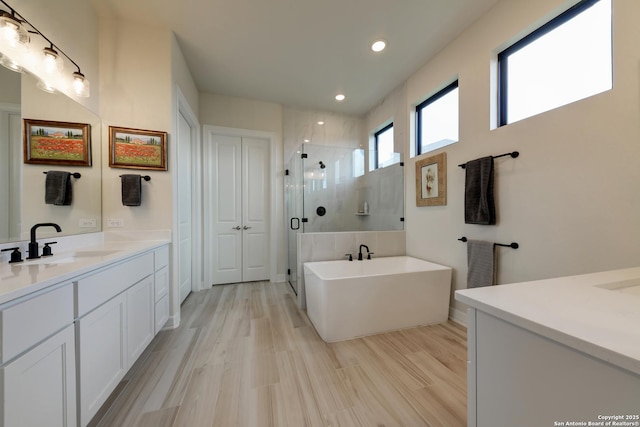 bathroom featuring wood-type flooring, independent shower and bath, and vanity