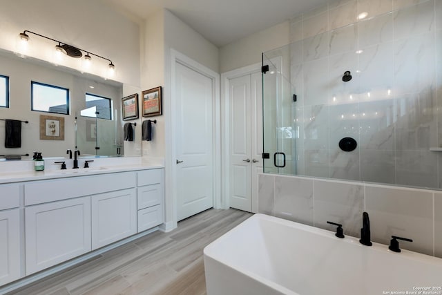 bathroom with shower with separate bathtub, wood-type flooring, and vanity