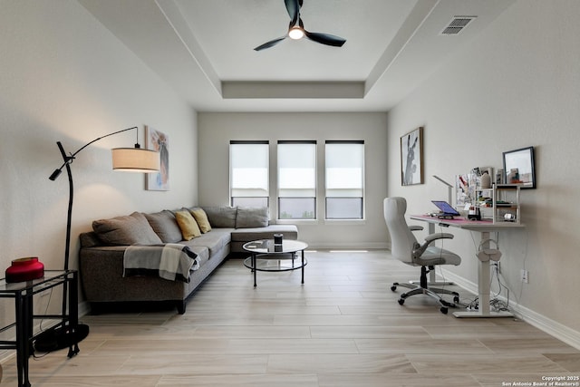 office space featuring ceiling fan, a raised ceiling, and light hardwood / wood-style flooring