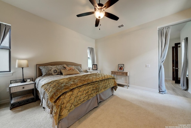 bedroom with multiple windows, light colored carpet, and ceiling fan