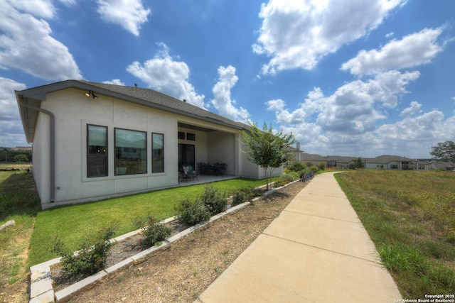 view of side of property with a patio area and a lawn