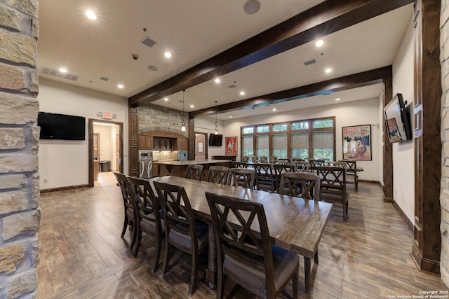 dining space featuring beamed ceiling and dark hardwood / wood-style flooring