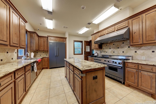 kitchen featuring high quality appliances, light stone countertops, a center island, and light tile patterned floors