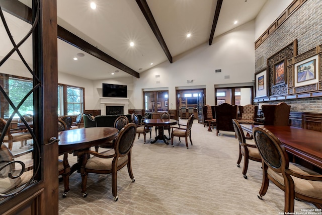 dining area featuring beamed ceiling, light colored carpet, and high vaulted ceiling