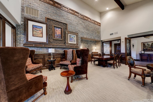 sitting room featuring light colored carpet, beam ceiling, and a high ceiling