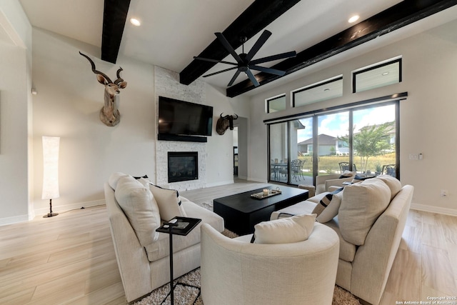 living room with ceiling fan, a fireplace, beam ceiling, and light hardwood / wood-style flooring