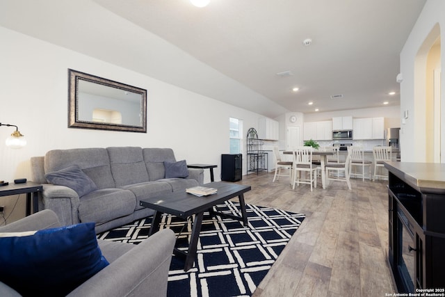 living room featuring lofted ceiling and light hardwood / wood-style floors