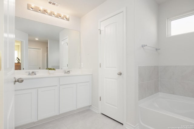 bathroom featuring vanity, a bath, and tile patterned floors