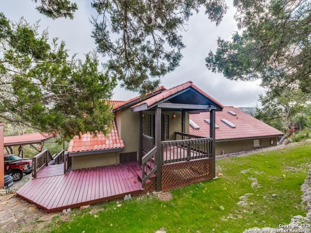 rear view of property with a wooden deck and a yard