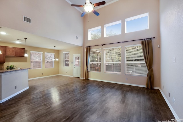 unfurnished living room featuring dark hardwood / wood-style flooring, ceiling fan, and a high ceiling