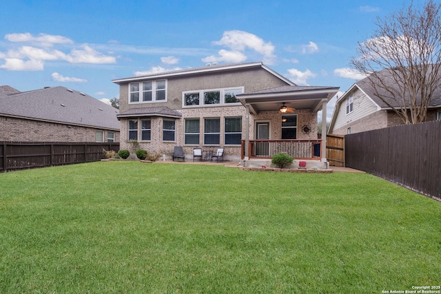 back of property featuring ceiling fan and a lawn