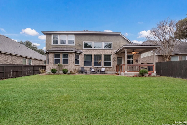 back of house featuring ceiling fan and a yard