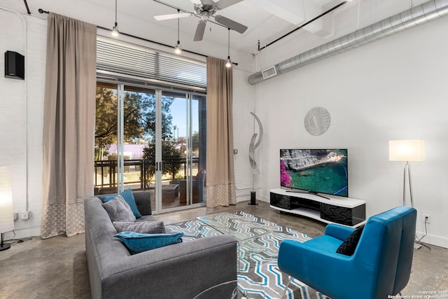 living room featuring ceiling fan, a towering ceiling, and concrete flooring