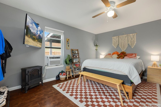 bedroom featuring cooling unit, ceiling fan, dark hardwood / wood-style floors, and a wood stove