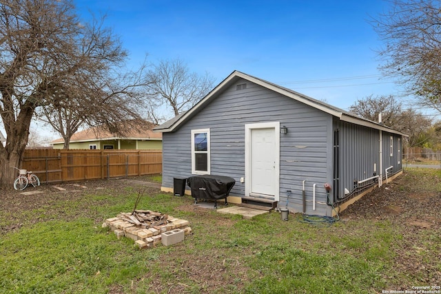 back of house with a yard and a fire pit