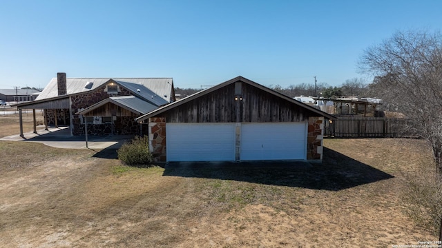 view of front of property with a garage, an outdoor structure, a carport, and a front lawn