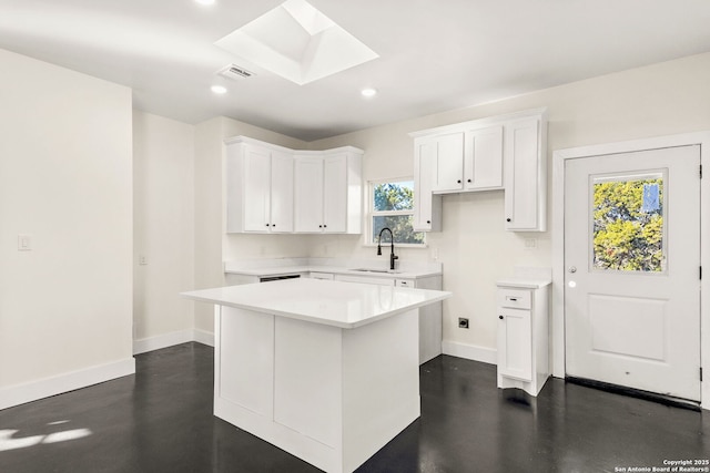 kitchen featuring white cabinetry, a center island, sink, and a skylight