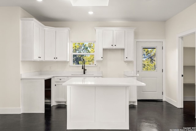 kitchen with white cabinetry, a center island, sink, and a healthy amount of sunlight