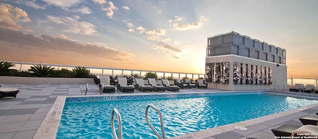 pool at dusk featuring a patio area