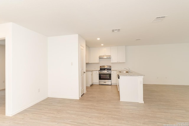 kitchen featuring white cabinetry, sink, stainless steel gas range, and light hardwood / wood-style flooring