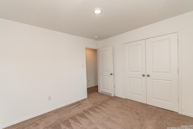 unfurnished bedroom with light colored carpet and a closet