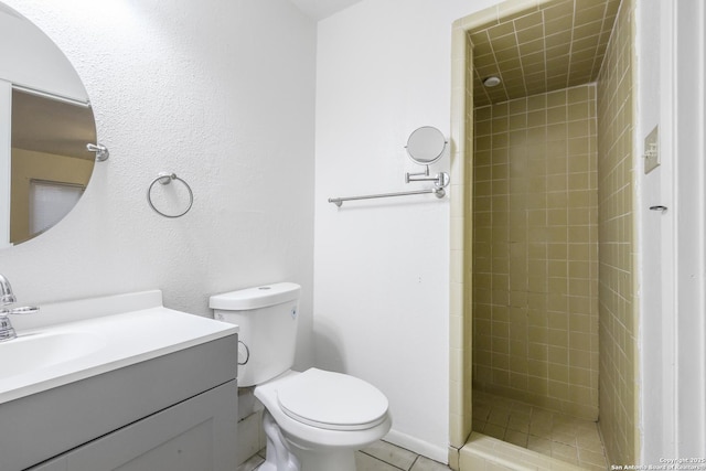 bathroom featuring a tile shower, vanity, tile patterned flooring, and toilet