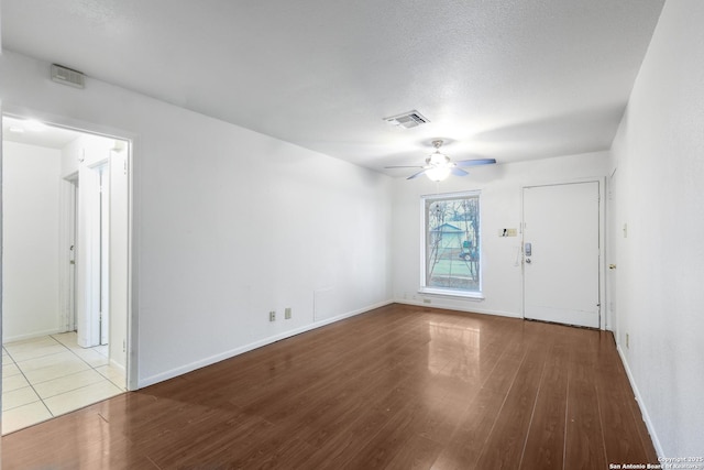 empty room with a textured ceiling, light hardwood / wood-style floors, and ceiling fan