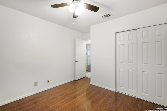 unfurnished bedroom with dark wood-type flooring, ceiling fan, and a closet