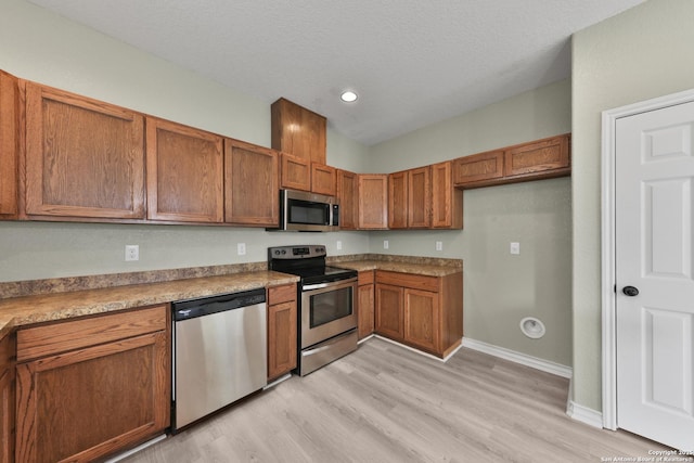 kitchen with stainless steel appliances, light hardwood / wood-style floors, and a textured ceiling