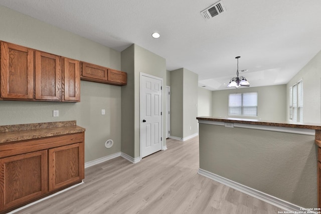 kitchen with hanging light fixtures, an inviting chandelier, and light hardwood / wood-style flooring