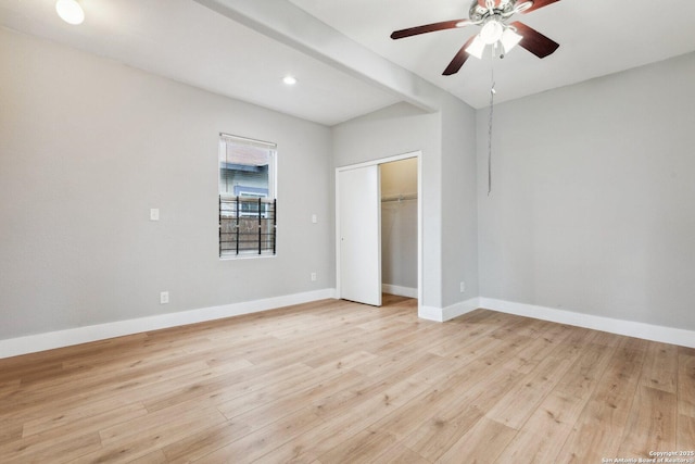 unfurnished bedroom with beam ceiling, ceiling fan, light hardwood / wood-style floors, and a closet