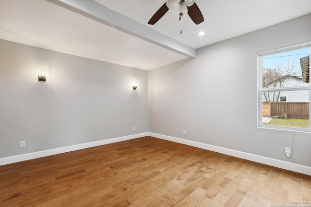 empty room with ceiling fan, wood-type flooring, and beam ceiling