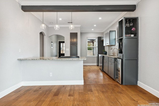 kitchen with sink, light stone counters, beverage cooler, stainless steel dishwasher, and kitchen peninsula