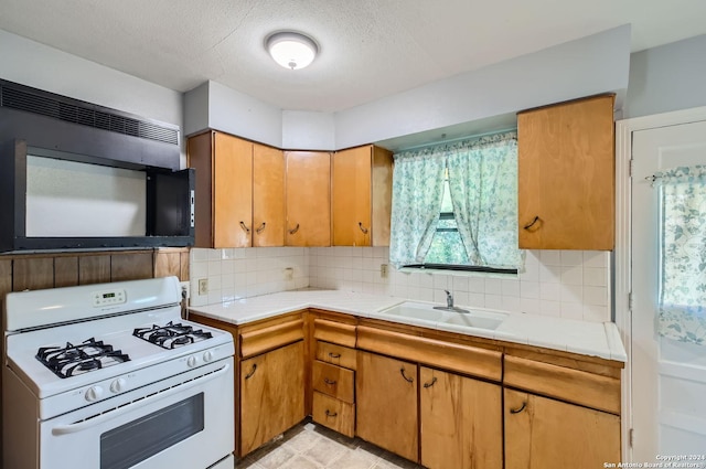 kitchen with sink, white gas stove, a textured ceiling, tile counters, and backsplash